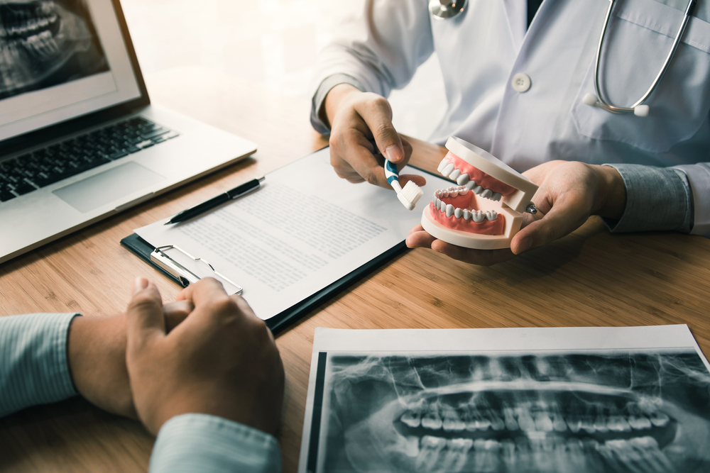 dentist showing patient dental x-rays and model of dentures